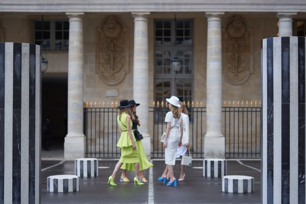 4 women in fashionable clothing standing outside a building with classical architecture