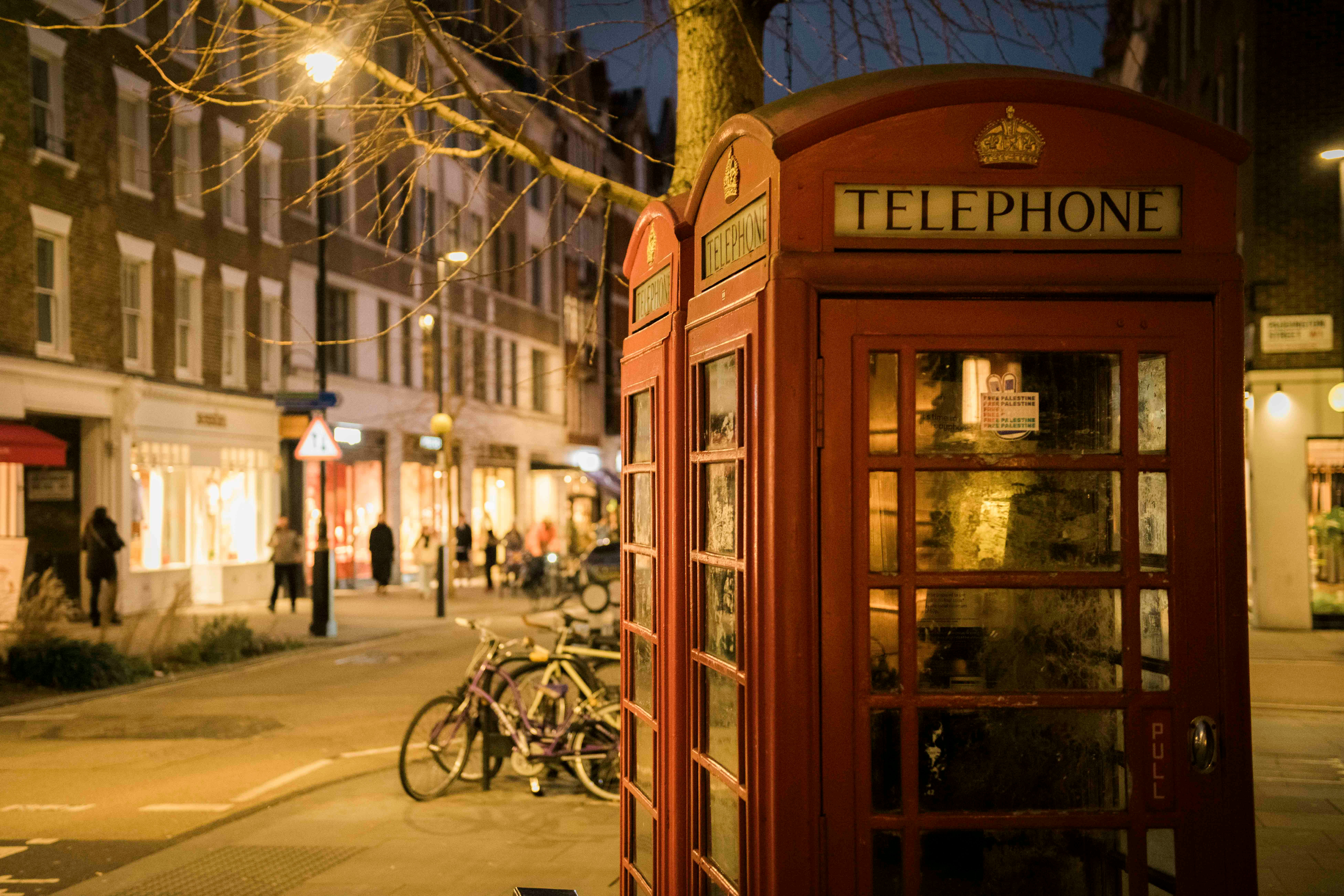 Red London Telephone Box on street at night
