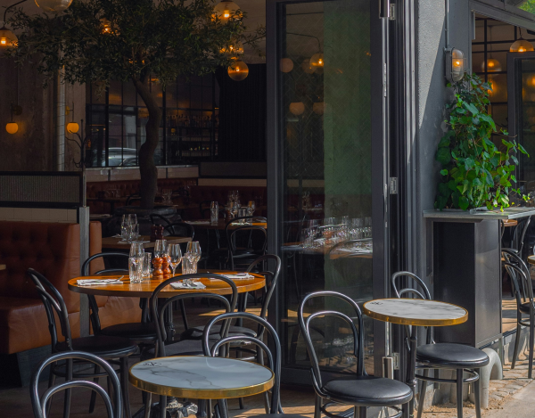 A cafe front with open bay doors and tabels without people
