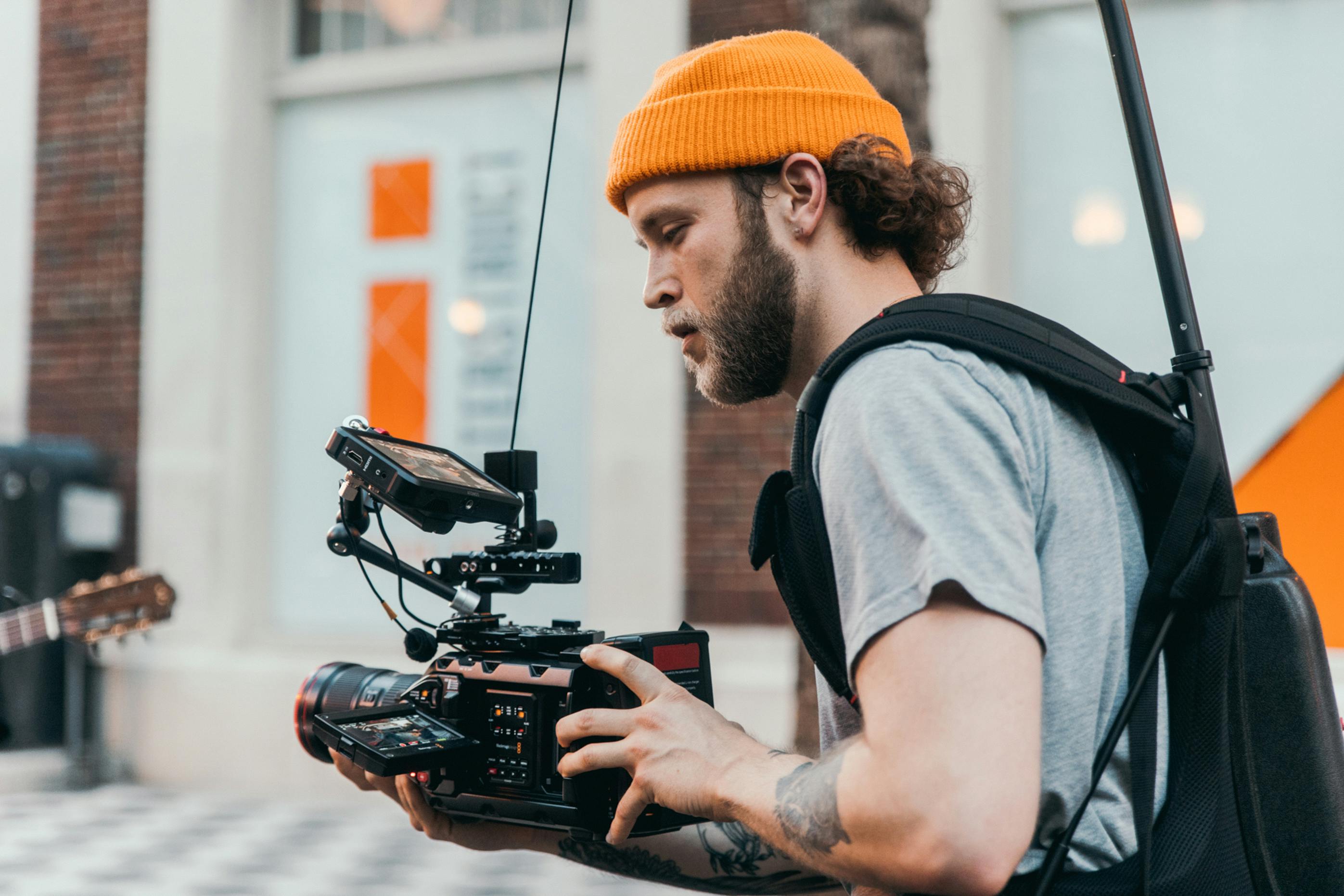 Man in london in beanie hat, filming on the street