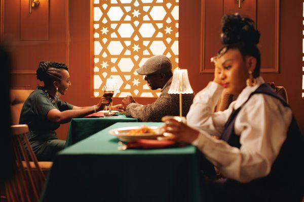Woman in foreground dining on own, with a couple in background