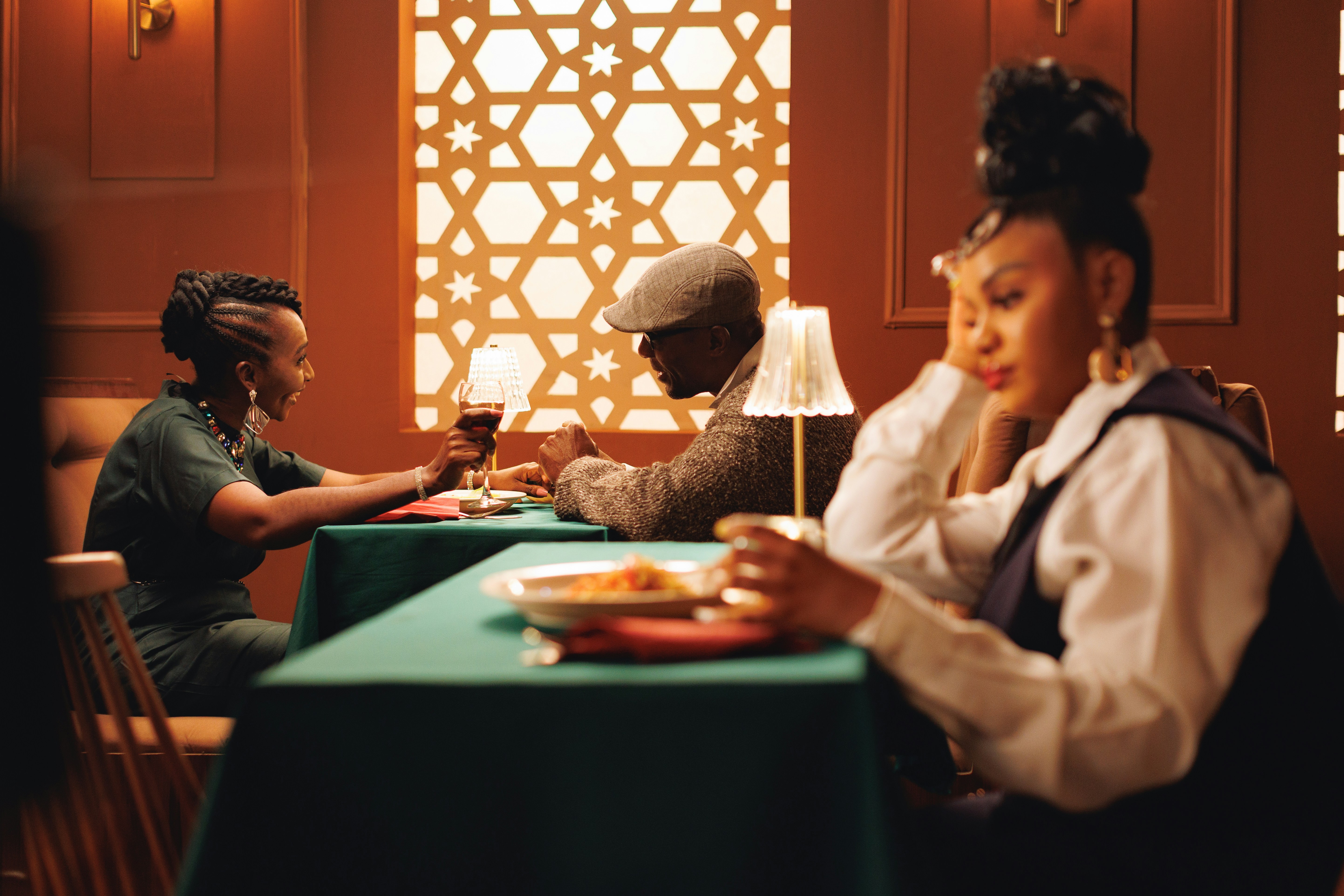 Woman in foreground dining on own, with a couple in background